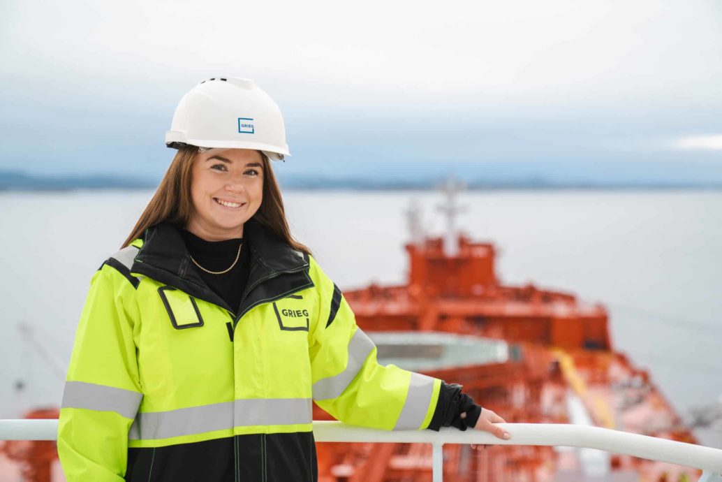Picture of ship agent Åsne Fjellsbø wearing a Grieg helmet and anorak onboard a vessel.